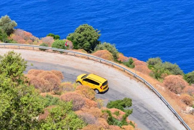 Yellow car driving on a scenic coastal road overlooking the blue sea in Halkidiki, Greece