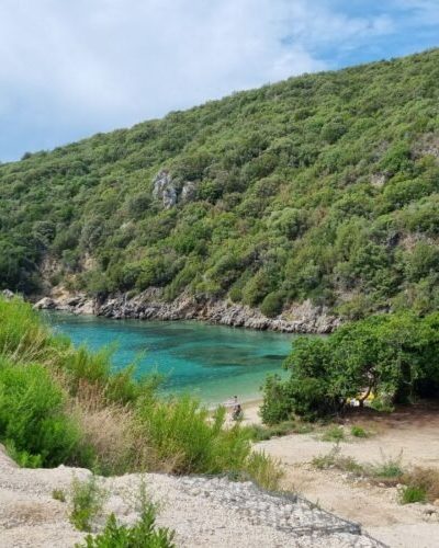 A secluded turquoise beach with crystal clear water surrounded by green hills near Parga, Northern Greece